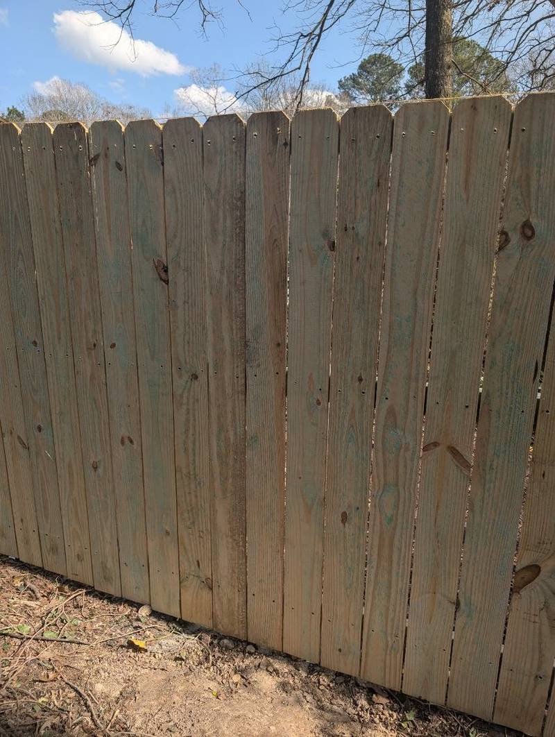 A newly built wooden dog-ear privacy fence under a blue sky